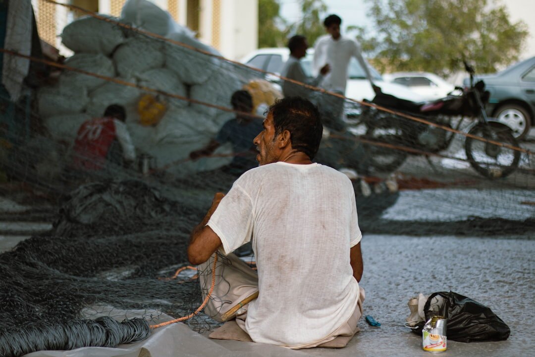 Elderly Danish fisherman mending nets at a harbor